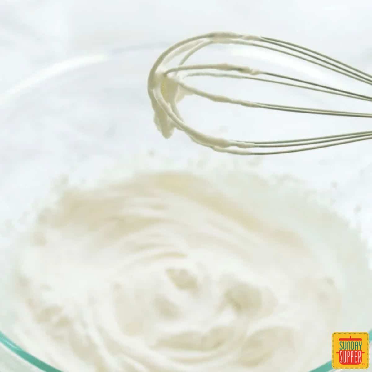 whipped cream in a bowl with a whisk