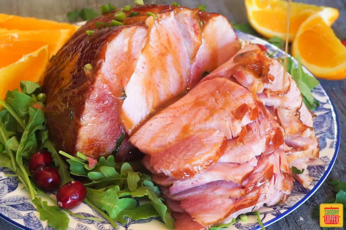 honey glazed ham on a blue and white plate with slicse of orange