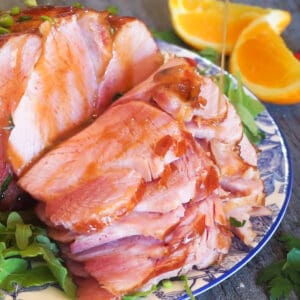 honey glazed ham on a blue and white plate with slicse of orange