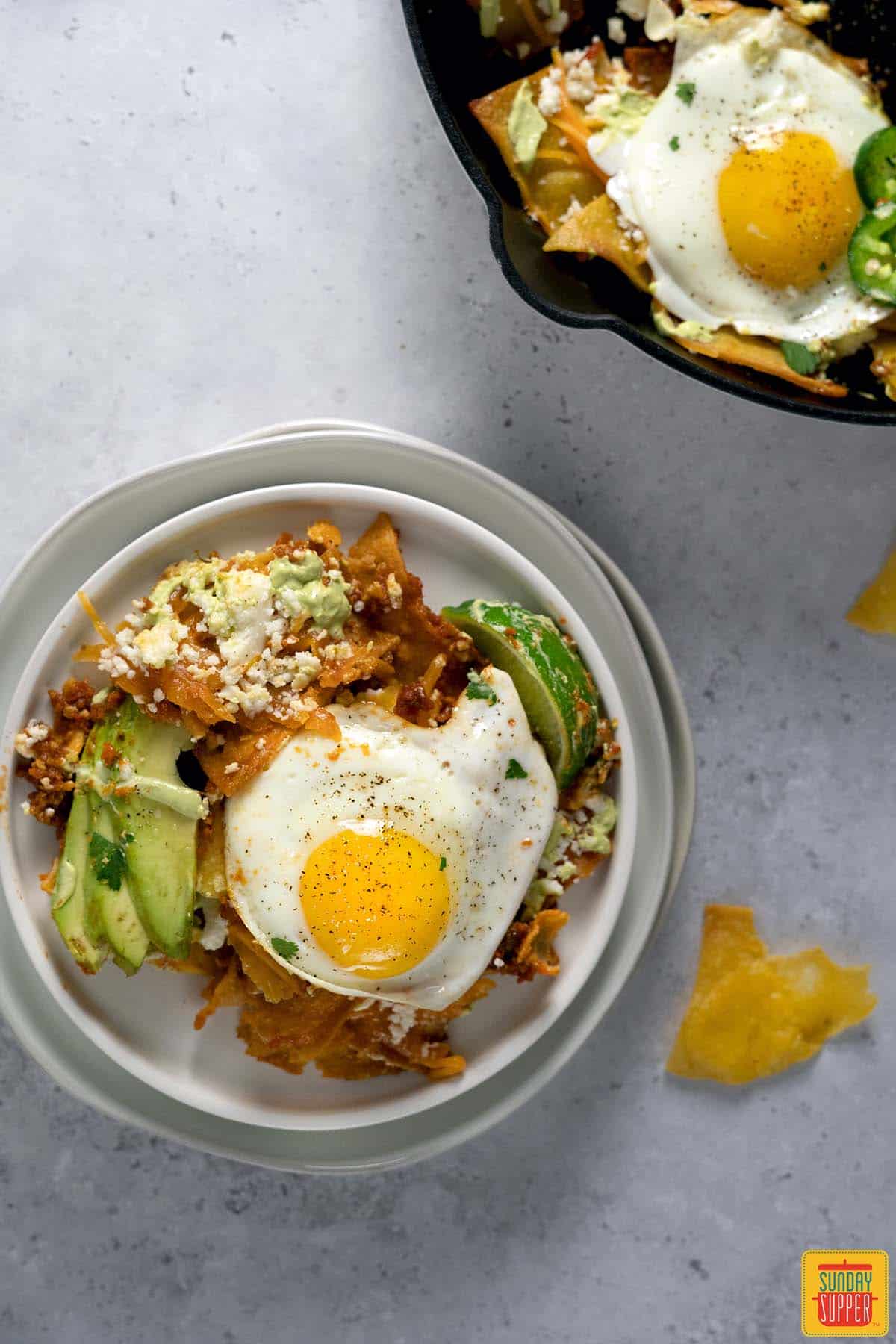 chilaquiles on a white plate next to a pan