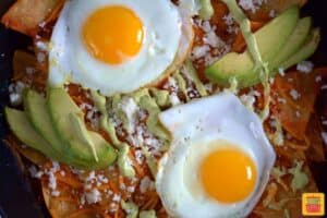 fried eggs on top of chilaquiles in a pan