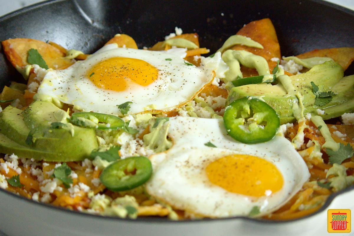 fried eggs on top of chilaquiles up close in a pan