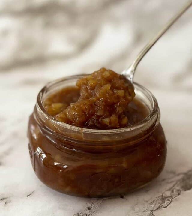 pineapple ham glaze in a clear jar with a metal spoon inside the jar