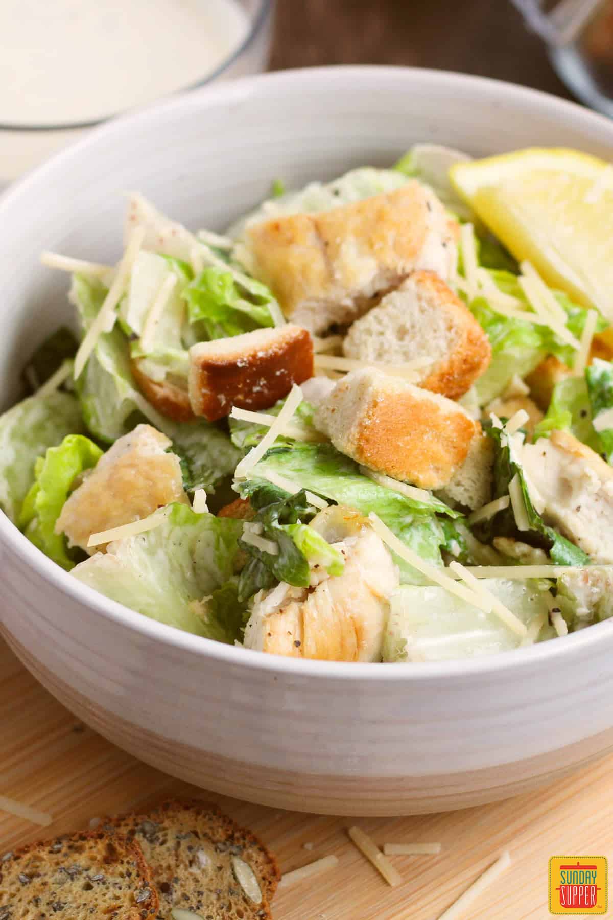a dish of caesar salad on a cutting board with bread slices