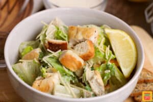 a completed dish of caesar salad with chicken and croutons