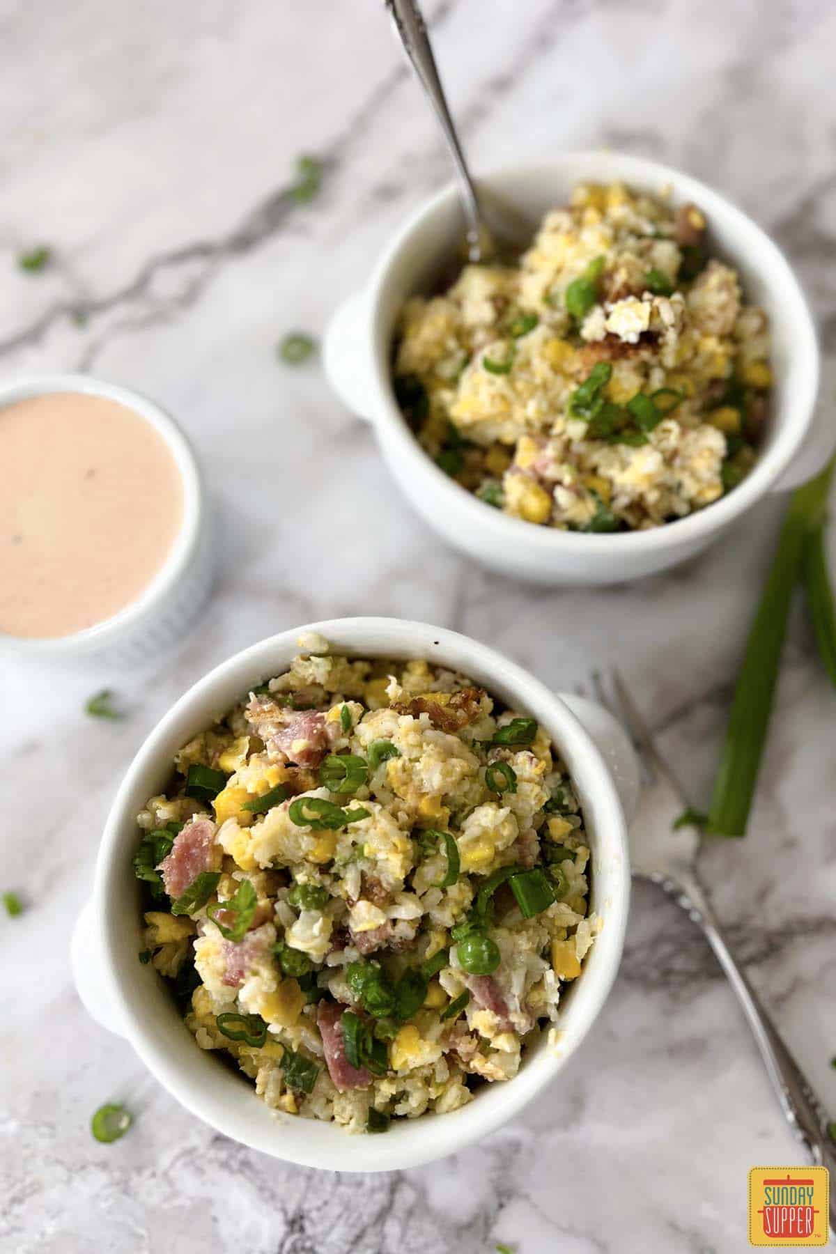 two bowls of ham fried rice with forks