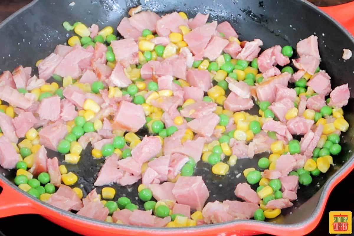sauteing ham with peas and corn in oil