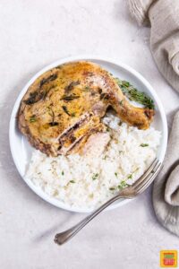 slow cooker chicken leg quarters on a plate with rice and fresh herbs