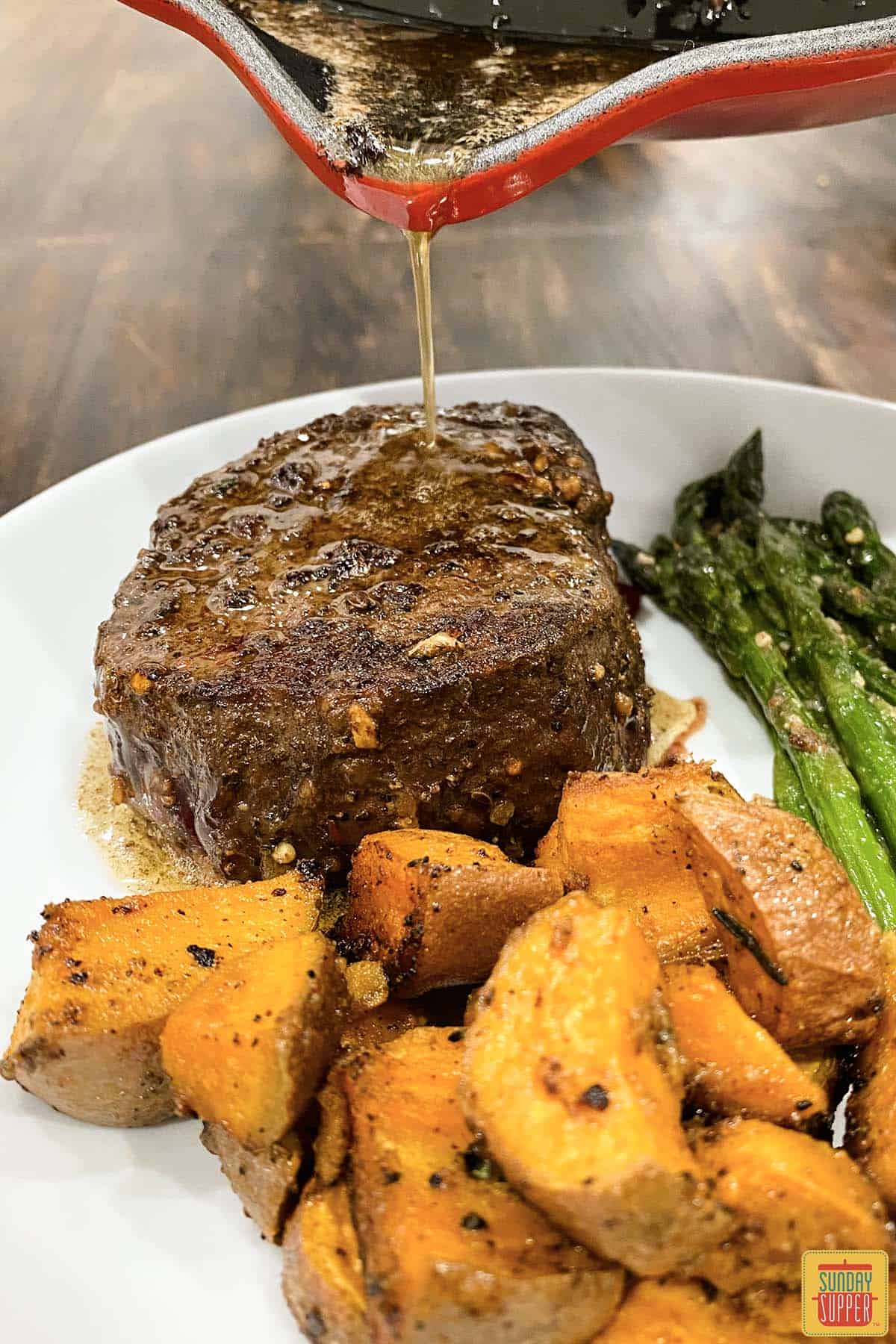 pouring butter sauce from pan over filet mignon on plate