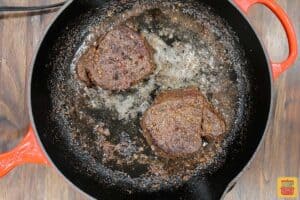 searing filet mignon in a cast iron pan