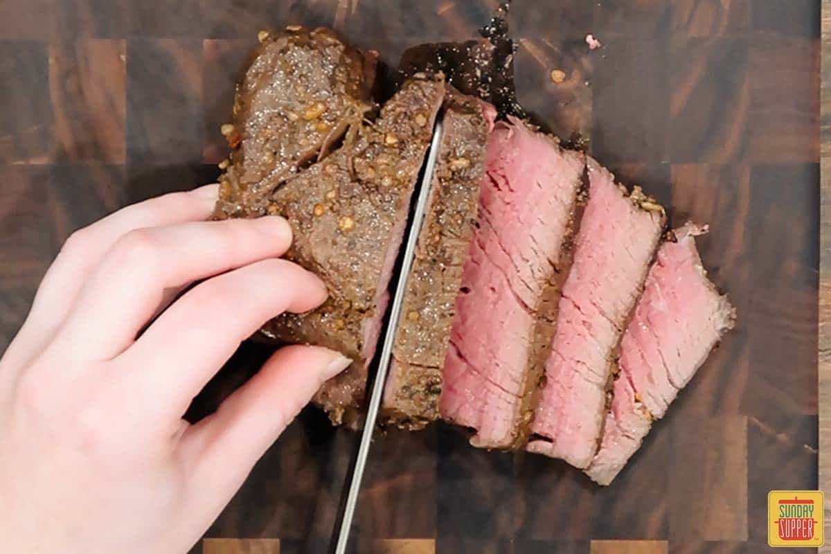 slicing sous vide filet mignon on a cutting board