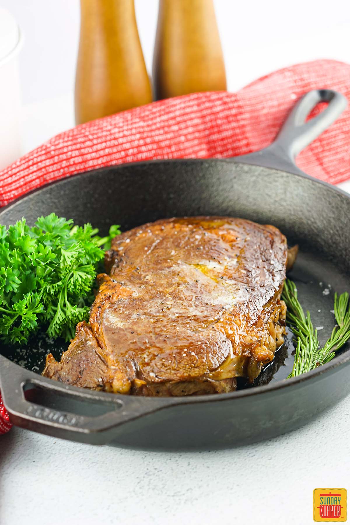 sous vide ribeye steak in a cast iron pan with fresh herbs
