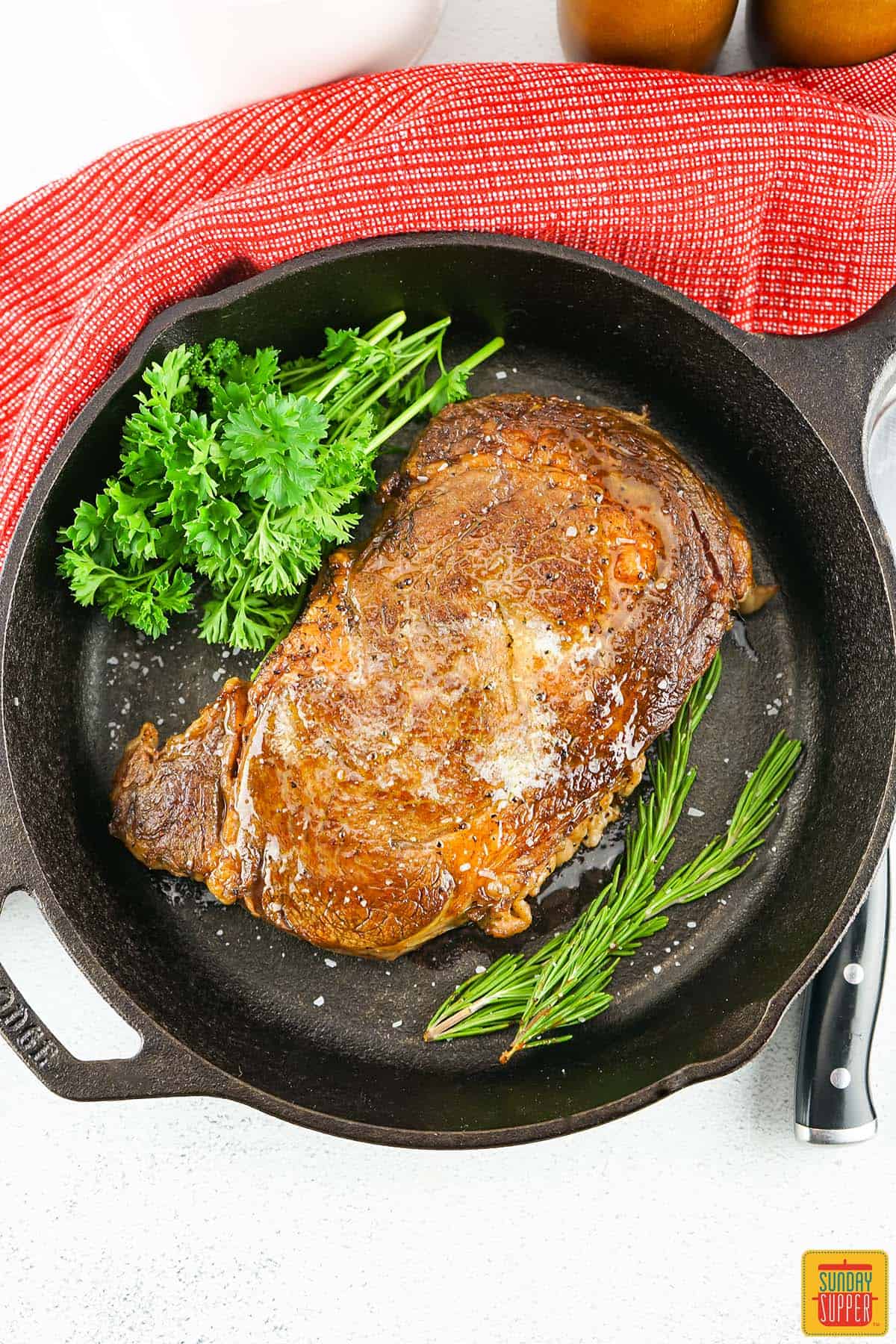 fresh herbs in a cast iron pan with a sous vide ribeye steak