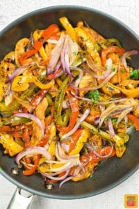 completed chicken fajitas in a pan with a cilantro garnish