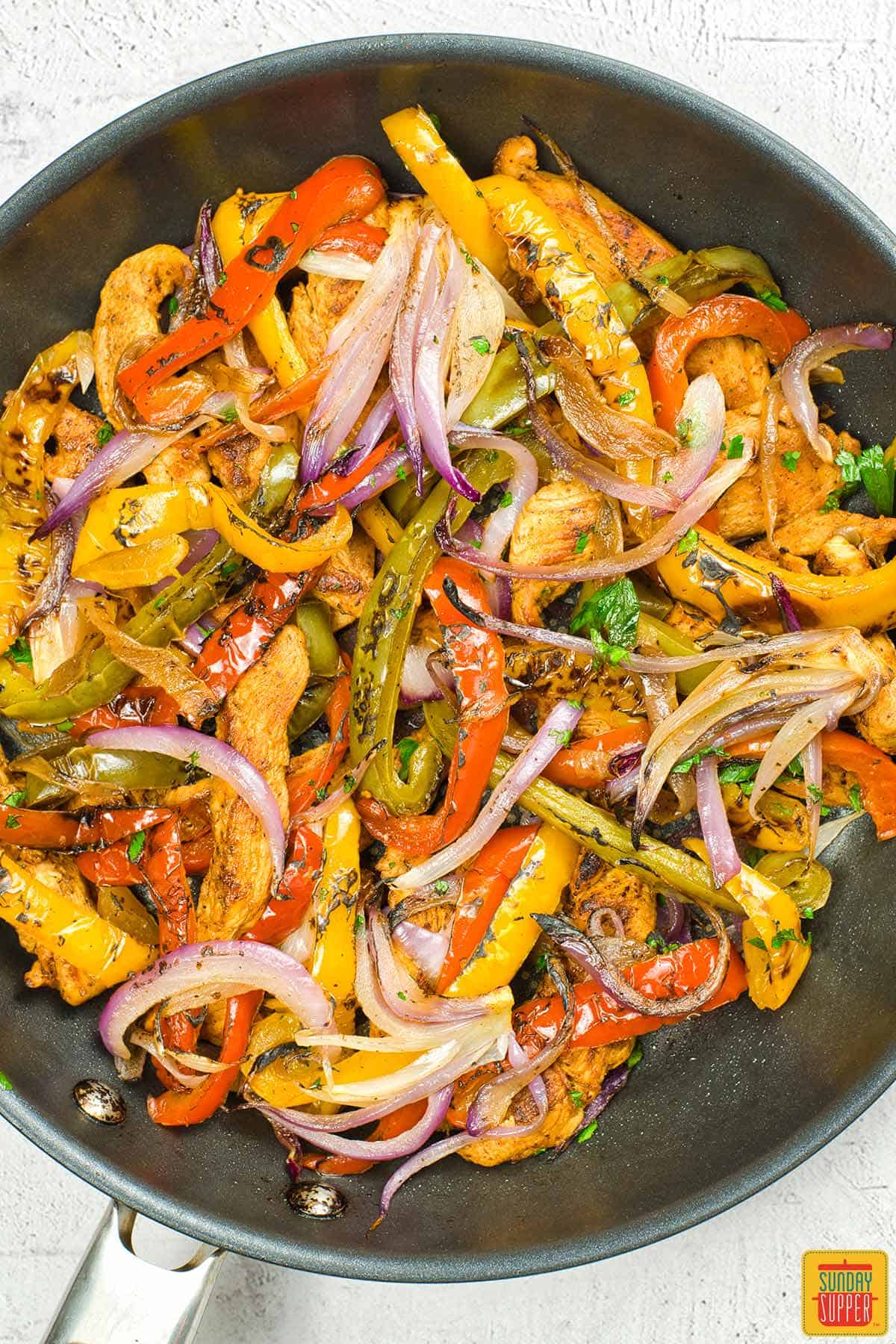 completed chicken fajitas in a pan with a cilantro garnish