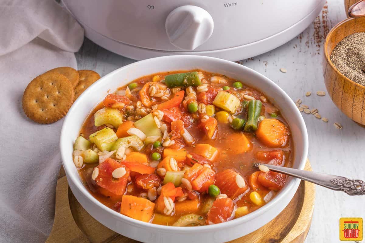 slow cooker vegetable soup in a white bowl with a spoon