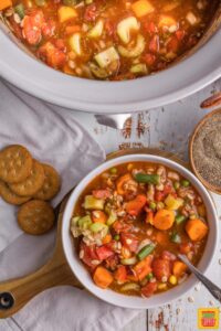 ritz crackers and a bowl of crockpot vegetable soup next to the slow cooker of soup
