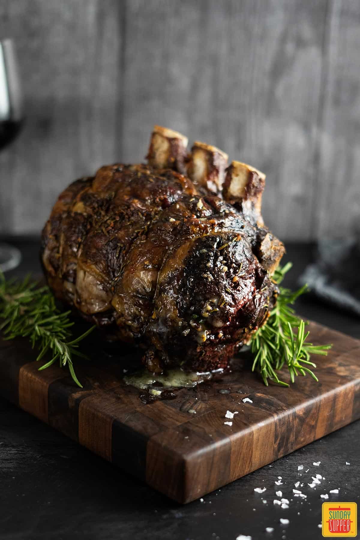 unsliced standing rib roast standing on a wood board