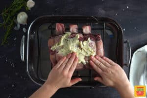 rubbing compound butter over standing rib roast