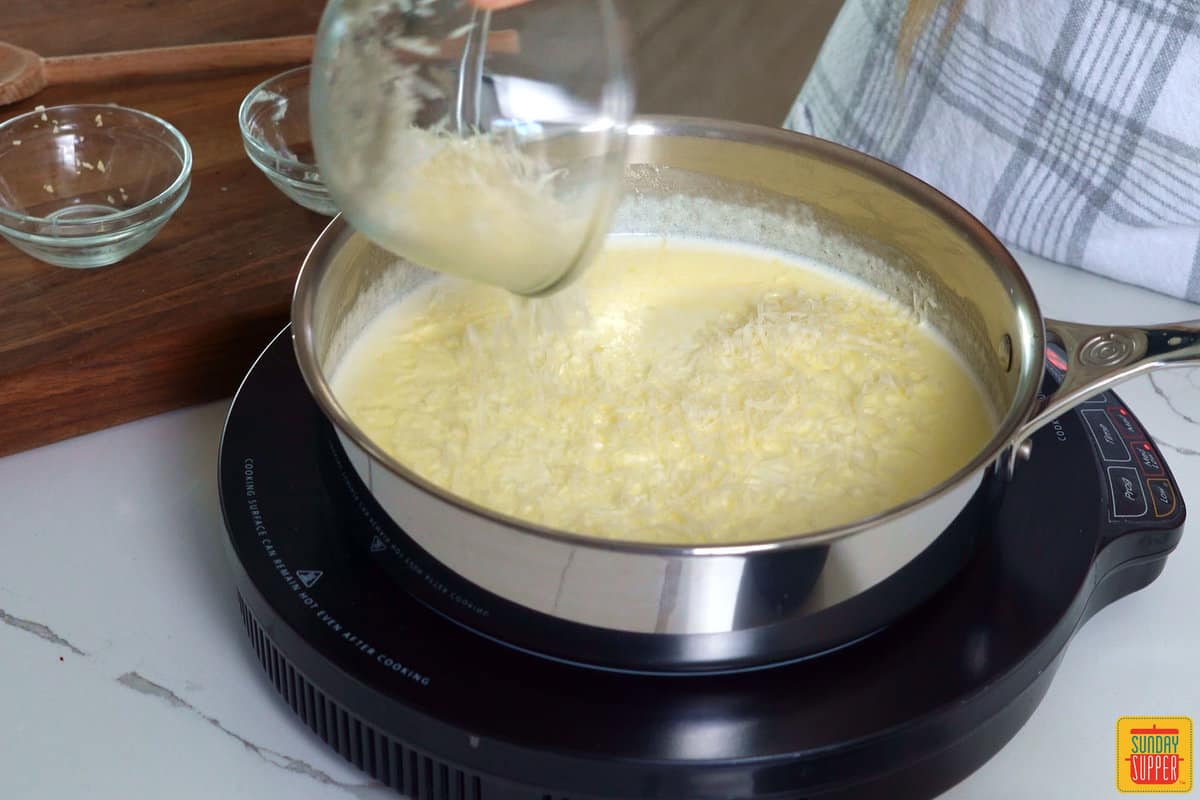 adding shredded parmesan cheese to a skillet