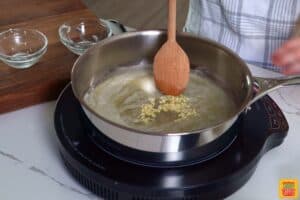 adding garlic to melted butter in a skillet