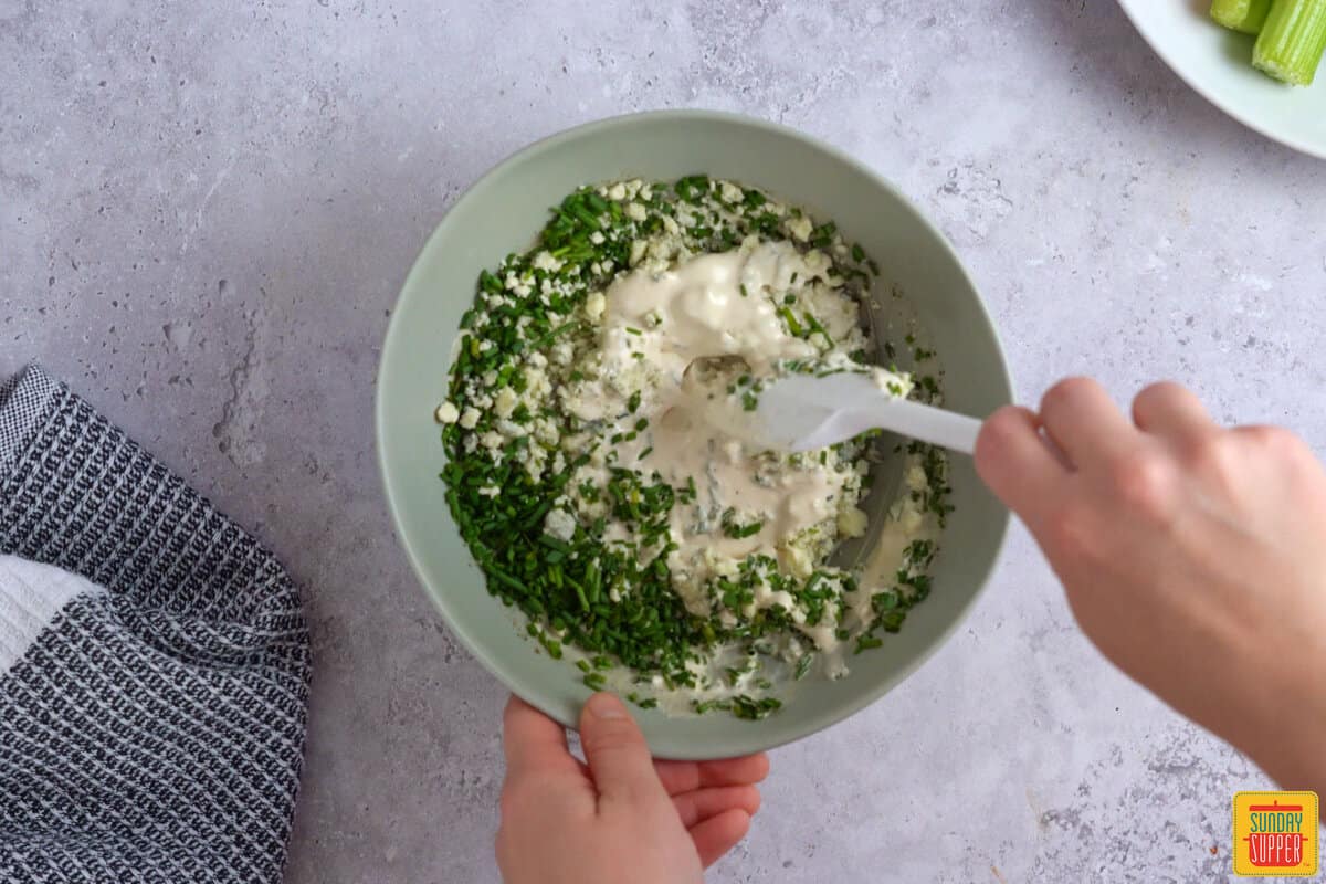 adding chives and blue cheese crumbles to blue cheese sauce