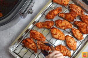 adding chicken wings to a baking dish to broil