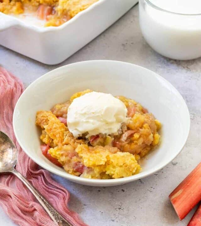 rhubarb dump cake in the background with a bowl of dump cake in front