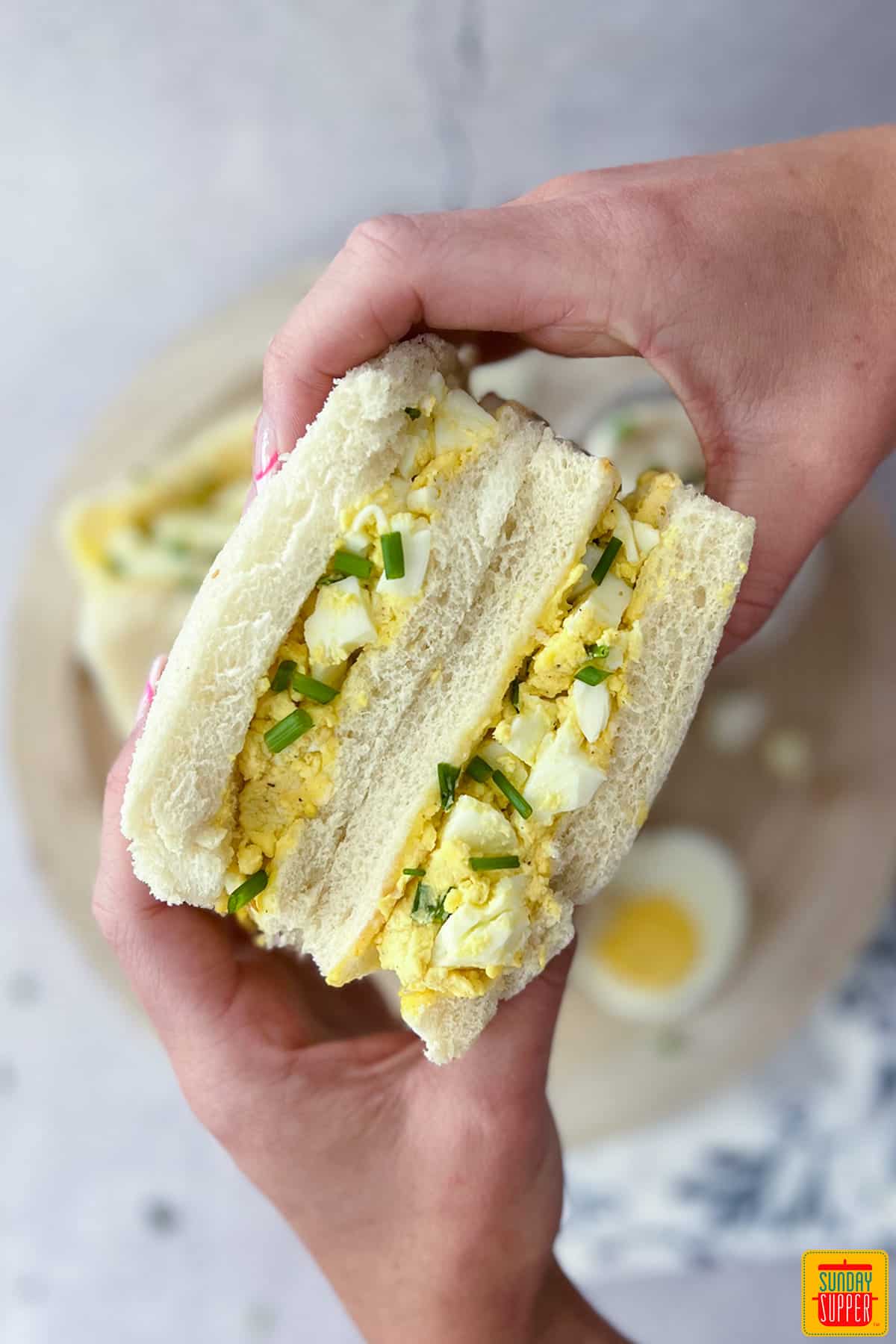 holding two egg sandwiches