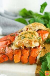 two grilled lobster tails on a serving board