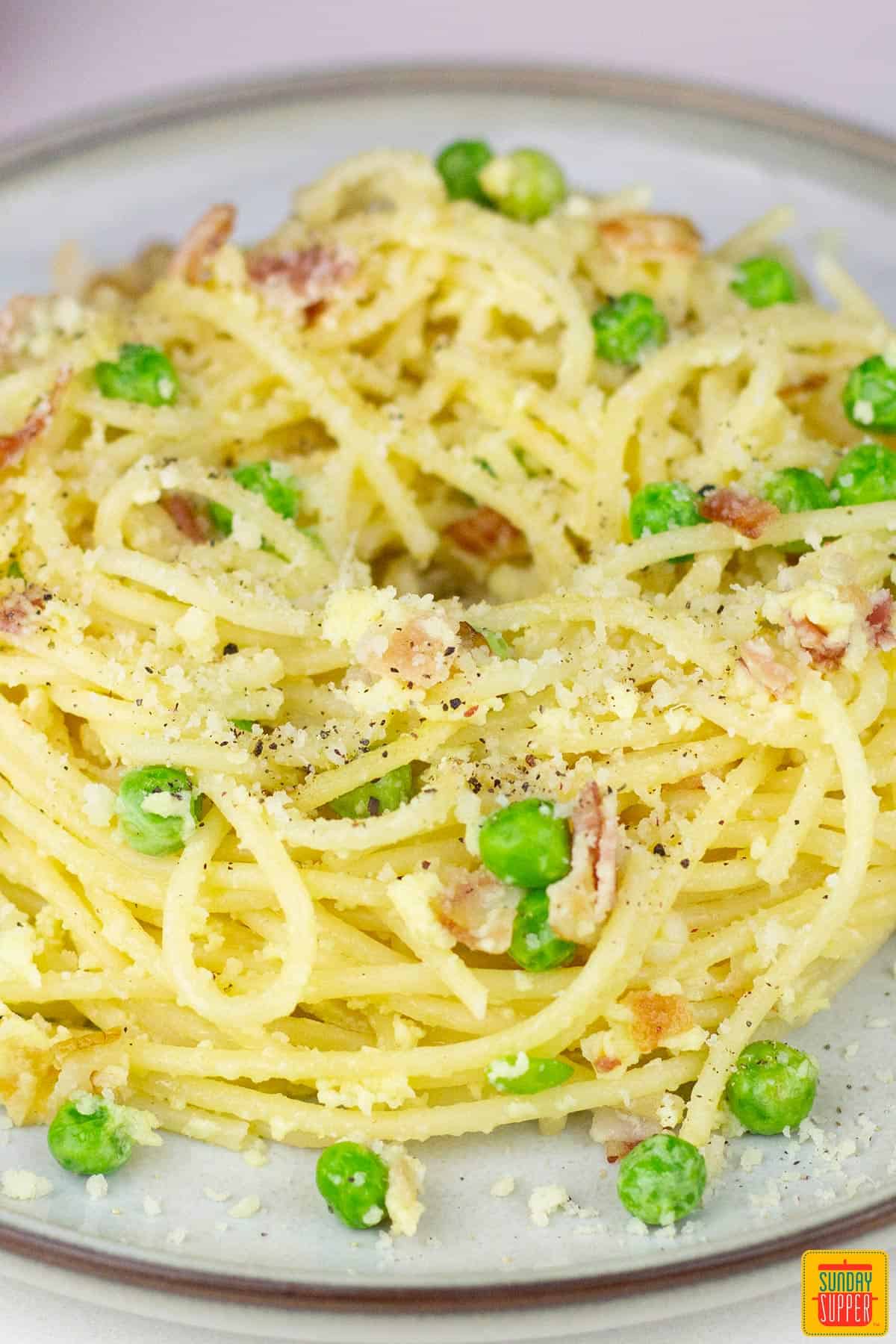 a plate filled with pasta carbonara garnished with parmesan cheese