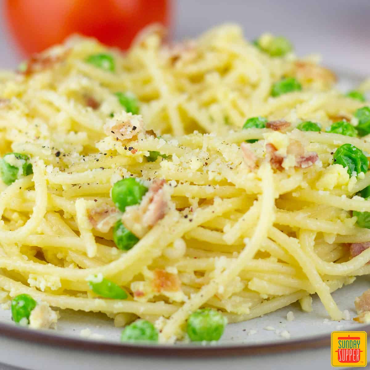 a closeup of a plate of pasta carbonara with peas and parmesan