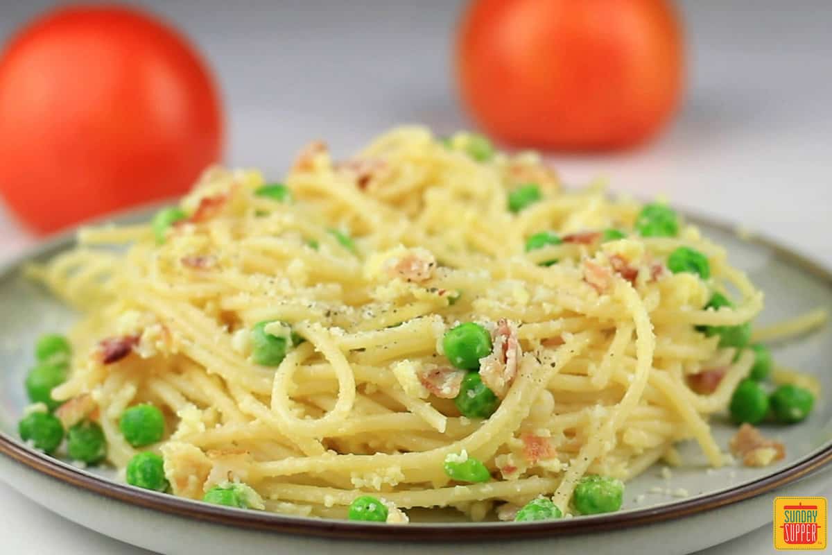 a completed plate of pasta carbonara with garnishing parmesan