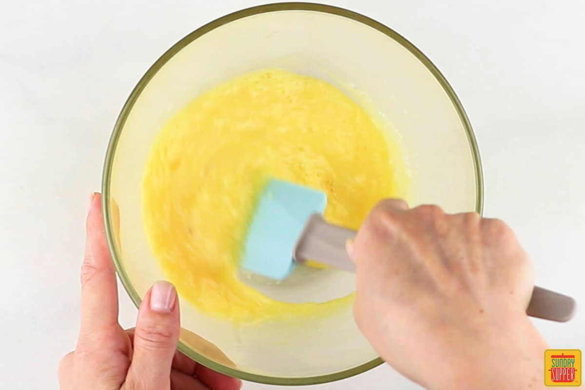 eggs and cheese being mixed together in a glass bowl