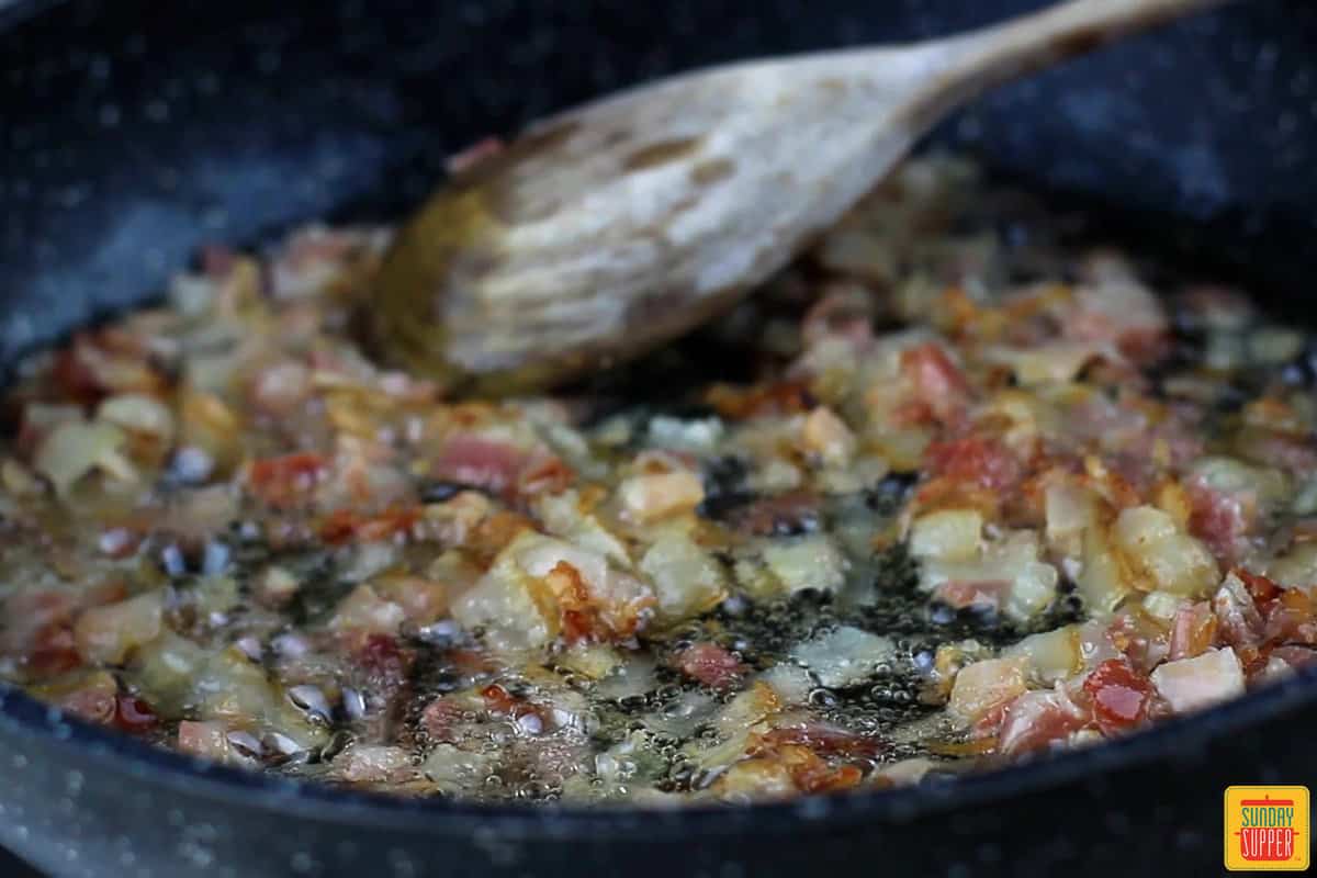 pancetta being fried in a pan with oil