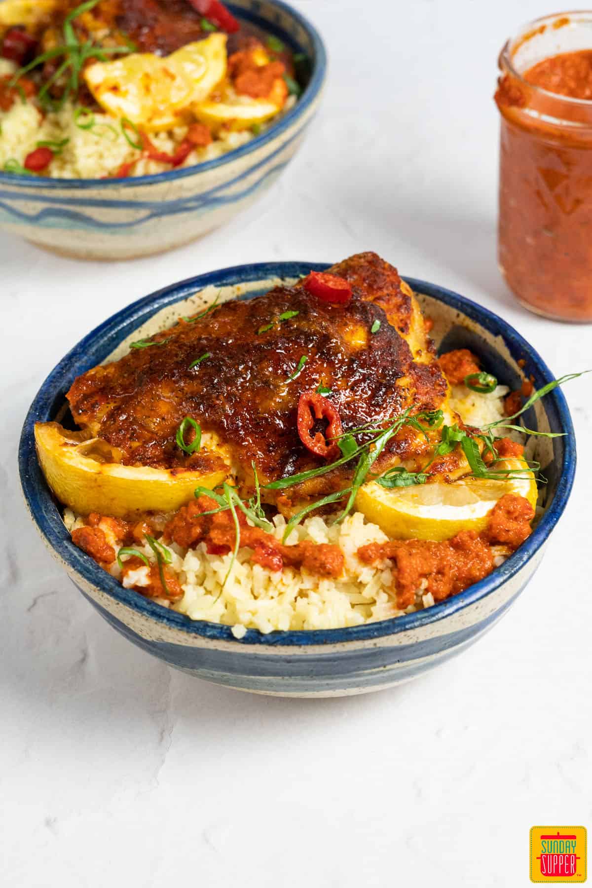 peri peri chicken in a bowl with rice and lemon wedges