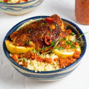 peri peri chicken in a bowl of rice with lemon wedges