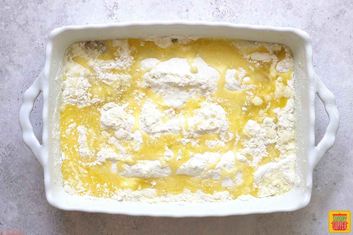 melted butter over cake mix in a white baking dish for rhubarb dump cake