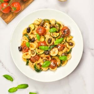orecchiette pasta salad with tomatoes and basil in a deep white plate