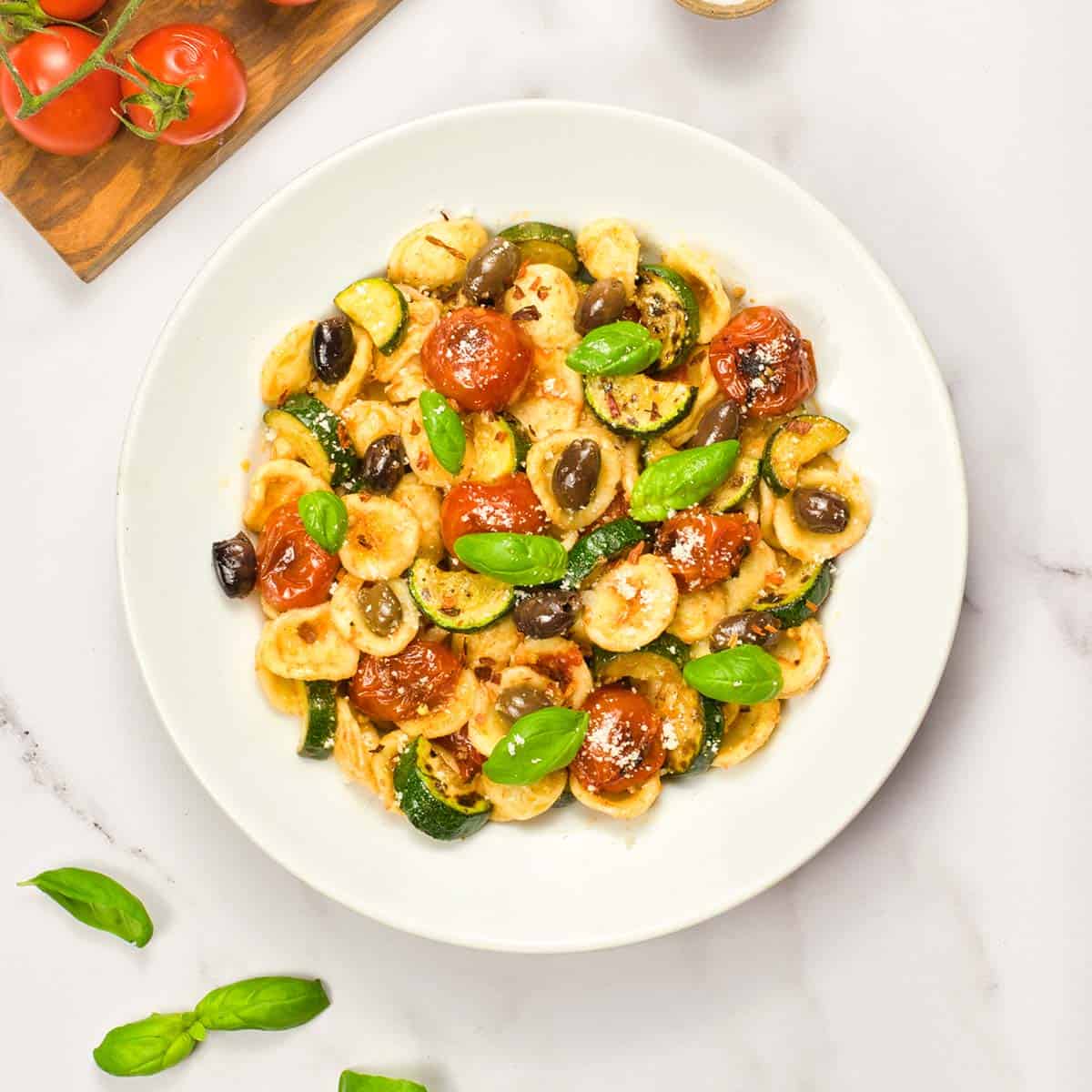 orecchiette pasta salad with tomatoes and basil in a deep white plate