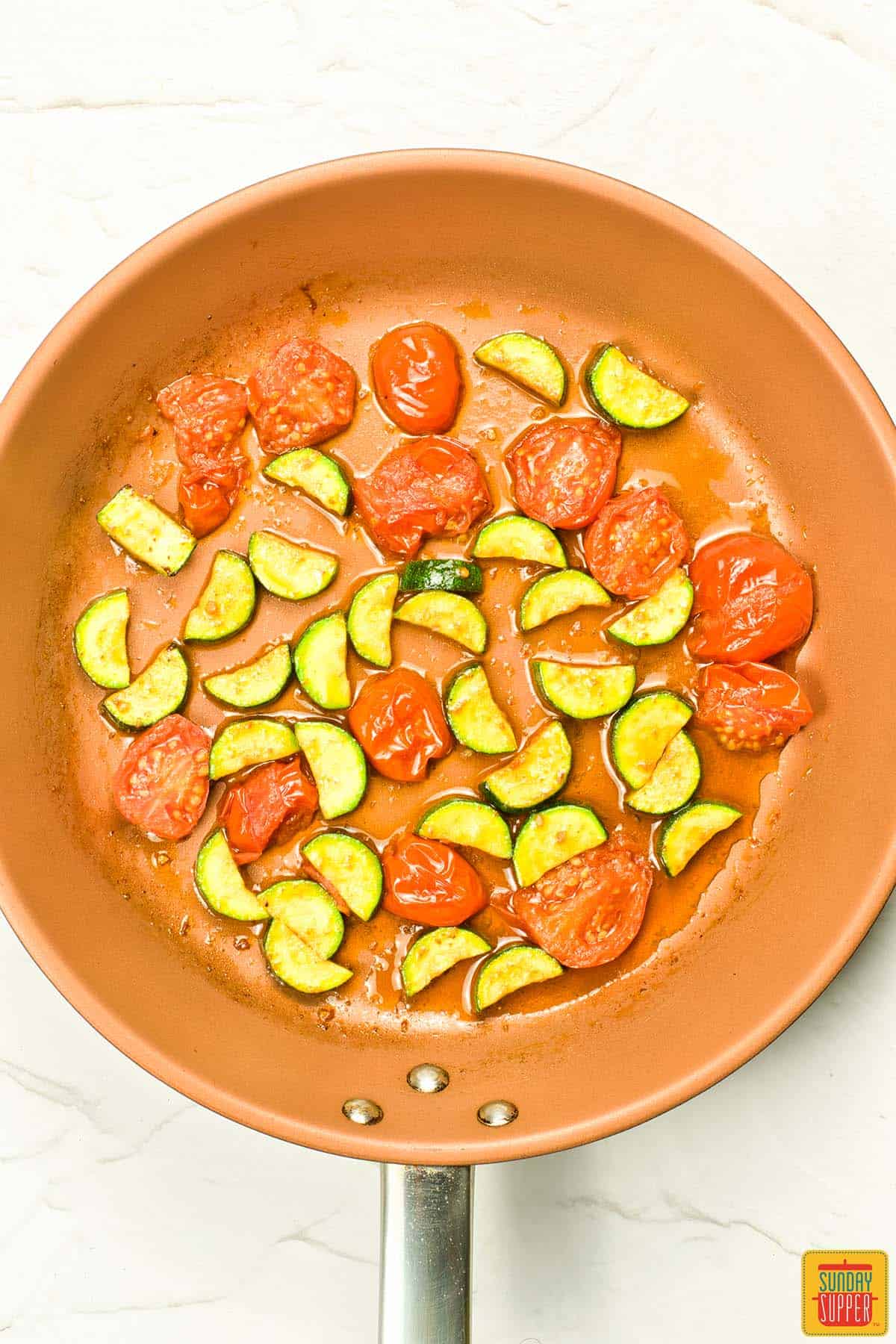 zucchini and tomatoes cooked in a pan