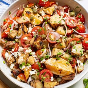 a white serving bowl of completed Mediterranean Potato Salad