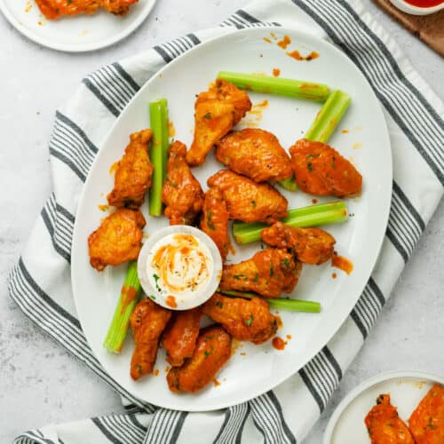 buffalo chicken wings on a white plate with celery sticks and dip
