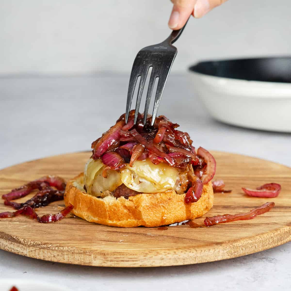 caramelized onions added to a burger with a fork