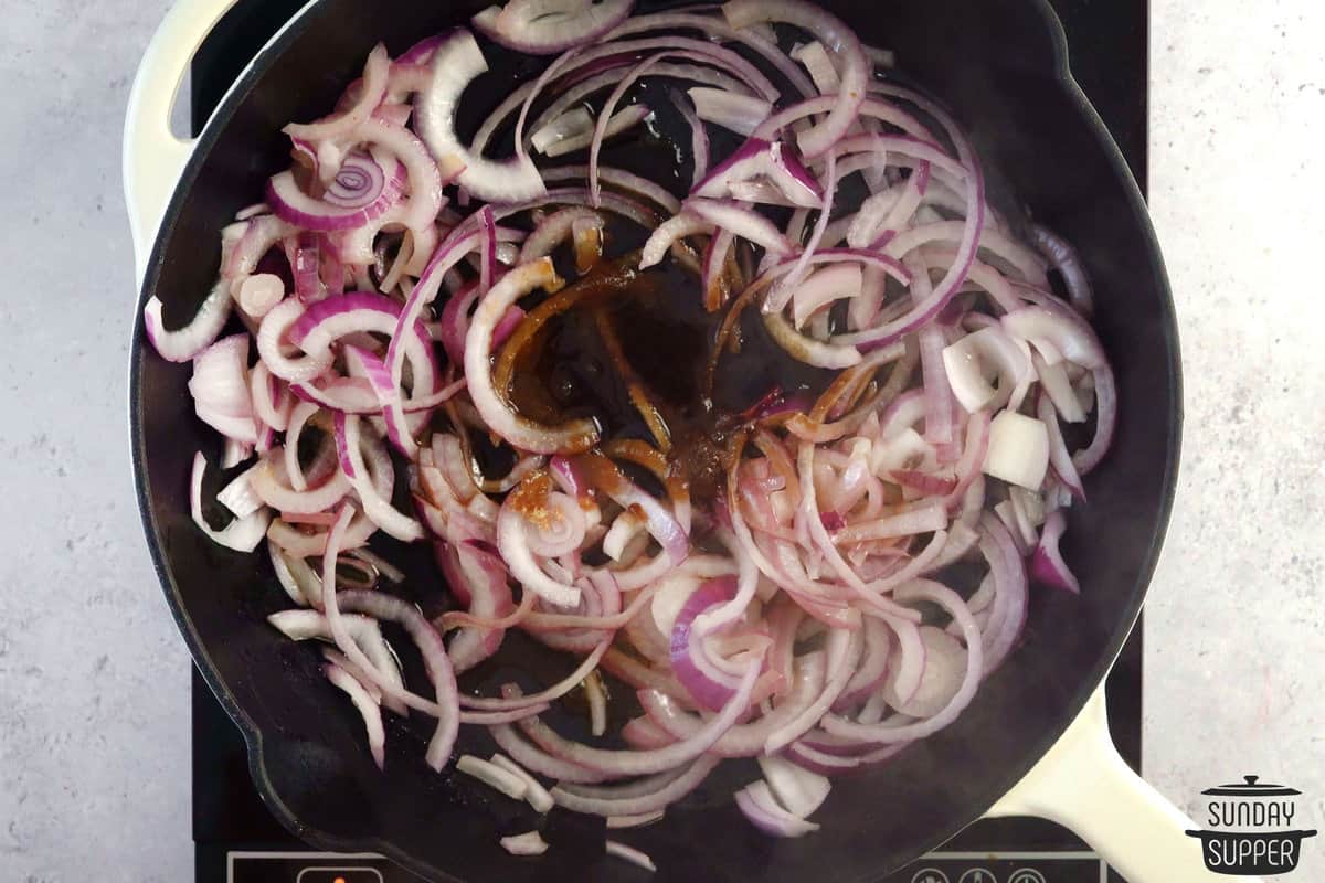 adding caramelized onions seasoning to pan with the onions