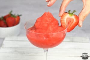 adding a strawberry to the rim of a glass of frose