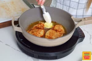 adding butter to the pan with the chicken breasts