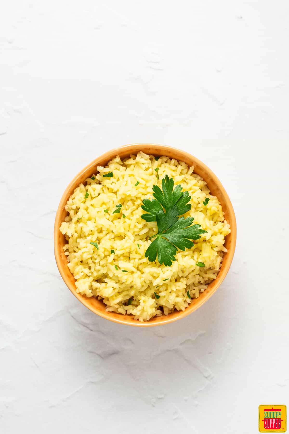 portuguese rice in a orange bowl with cilantro