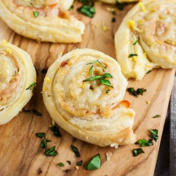 puff pastry pinwheels up close on a serving board with shredded basil