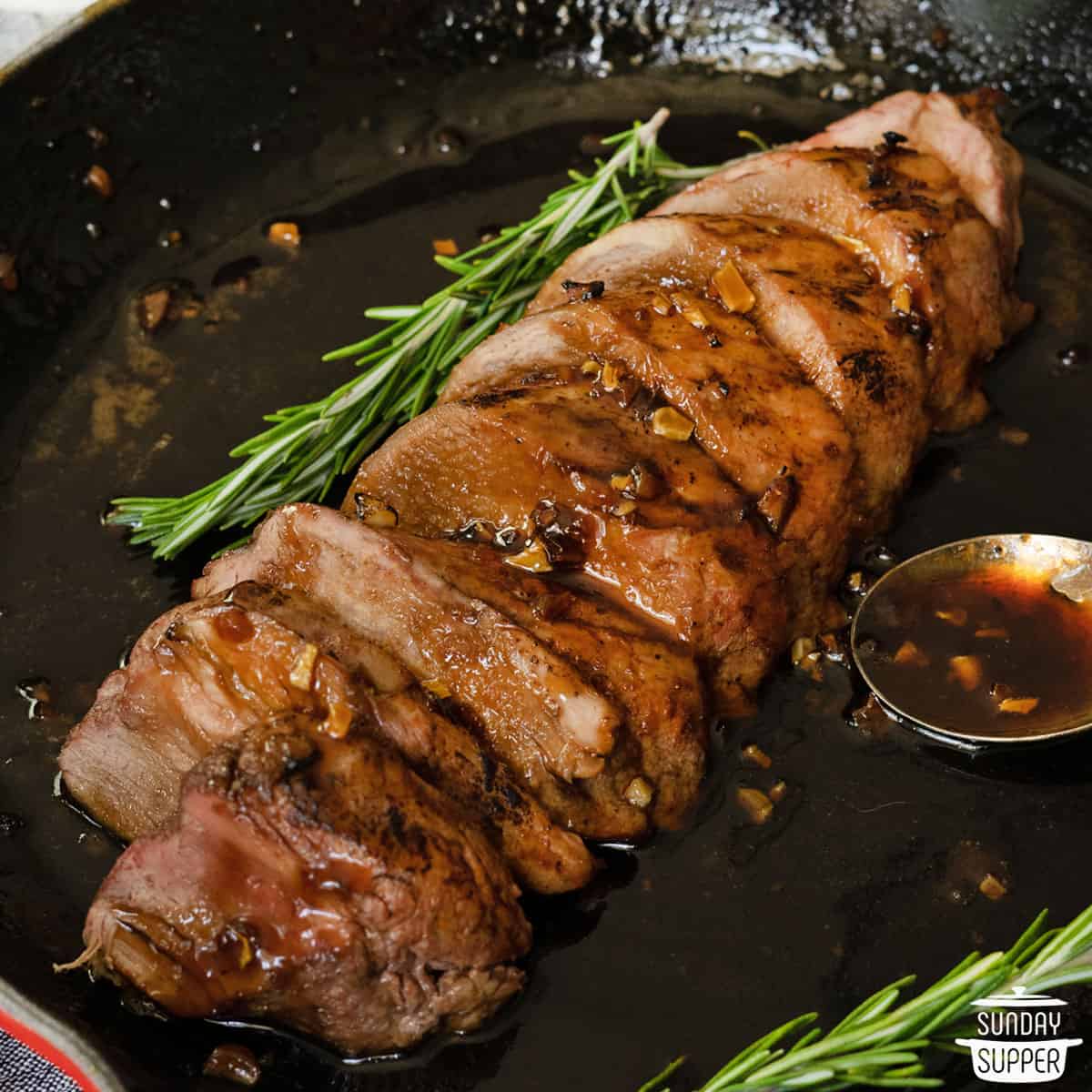 Roasted pork tenderloin sliced in a pan with honey garlic sauce